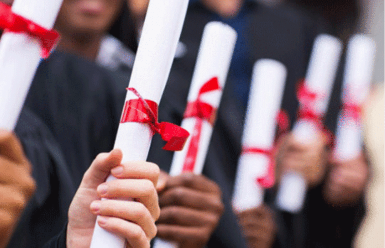 alt: Χέρια αποφοίτων που κρατούν ρολά πτυχίων δεμένα με κόκκινη κορδέλα during σημείου τελετής oρκωμοσίας