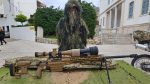 Στρατιώτης με στολή ghillie παρουσιάζει ελεύθερο σκοπευτή με τηλεσκοπικό σκοπευτήριο στην έκθεση οπλικών συστημάτων του Ελληνικού Στρατού Ξηράς στη Σάμο, Απρίλιος 2025.