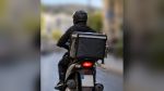 ιανομέας με μηχανάκι και θερμοσάκο σε δρόμο πόλης